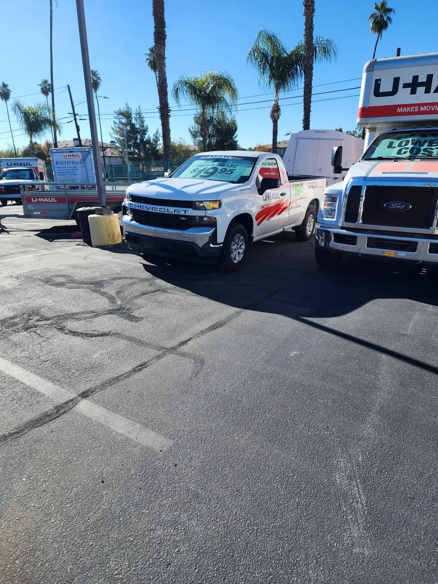 U-Haul trucks and trailers on the Circle C Storage lot — Chevrolet truck-share pickup, Ford U-Haul box truck, and U-Haul trailers under palm trees